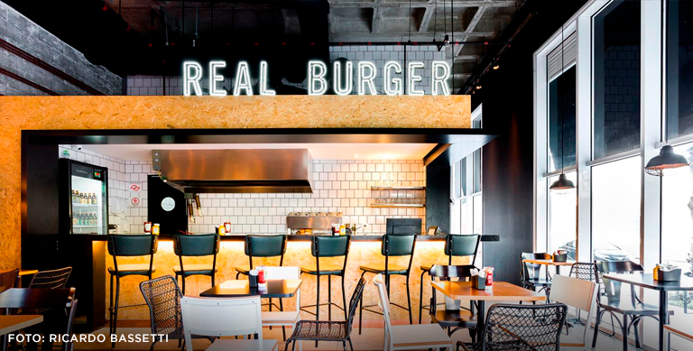 ambiente interno do Real Buger mostrando o letreiro em neon e a laje nervura
