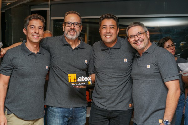 Quatro colaboradores sorrindo com um troféu da Atex